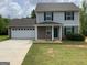 Charming home boasts light gray siding, green shutters, well-manicured lawn and ample driveway space at 253 Whistle Way, Locust Grove, GA 30248