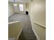A view looking down the staircase into an empty living room with carpeted floors and a fireplace at 253 Whistle Way, Locust Grove, GA 30248