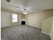 View of an empty living room featuring neutral paint, a fireplace, a ceiling fan, and carpeted floors at 253 Whistle Way, Locust Grove, GA 30248