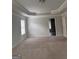 A large carpeted bedroom features a tray ceiling and a view to the ensuite bathroom at 1124 Pebble Creek Ln, Locust Grove, GA 30248