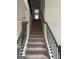Carpeted staircase with wrought iron spindles and wooden handrail leads to the upper level of the home at 1124 Pebble Creek Ln, Locust Grove, GA 30248