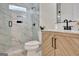 Bright bathroom with a glass-enclosed shower featuring marble tile, a wood vanity, and black hardware at 400 Walnut Grove Rd, Peachtree City, GA 30269