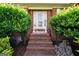 Charming brick home entrance with decorative shrubbery, steps and a glass front door at 70 Lake Charles Xing, Covington, GA 30016