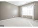 An empty bedroom is shown with neutral walls, white trim, neutral carpet, and a window dressed in sheer curtains at 2180 Briarwood Ct, Villa Rica, GA 30180