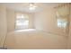 An empty bedroom is shown with a ceiling fan, white walls, neutral carpet, and windows draped in light colored sheers at 2180 Briarwood Ct, Villa Rica, GA 30180