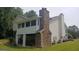 View of a home's rear exterior, highlighting a stone chimney and a screened-in porch at 2477 Briar Valley Way, Dacula, GA 30019