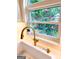 Close-up of the kitchen sink with a gold faucet, providing a charming view of the lush garden outside at 508 Caxton Ct, Peachtree City, GA 30269