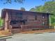 Rustic log home with a stone chimney, a covered front porch, and well-maintained landscaping at 150 Rockspray Rdg, Peachtree City, GA 30269