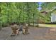 An outdoor fire pit area features wooden chairs and a gravel base surrounded by trees and greenery at 602 Embassy Ct, Peachtree City, GA 30269
