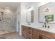 Bathroom featuring wood cabinets, dual sinks, large mirrors, and a walk-in shower with glass doors at 4731 H D Atha Rd, Covington, GA 30014