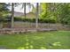 Serene backyard with a well-maintained lawn, a retaining wall, and a classic wooden fence at 4985 Rolling Rock Dr., Sugar Hill, GA 30518