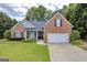 Inviting brick home with a well-manicured lawn, charming front porch, and a two-car garage at 4985 Rolling Rock Dr., Sugar Hill, GA 30518