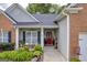 Charming front porch with seating area, attractive landscaping, and inviting red front door at 4985 Rolling Rock Dr., Sugar Hill, GA 30518