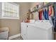 Bright laundry room features a window, washer, dryer, shelving, and hanging rack for fresh and convenient clothes care at 4985 Rolling Rock Dr., Sugar Hill, GA 30518