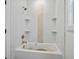 Modern white bathtub with tile surround and built-in shelves features stylish fixtures for a relaxing bath experience at 4751 H D Atha Rd, Covington, GA 30014