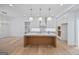 White kitchen with island, pendant lighting, marble countertops, and hardwood floors in new home at 4751 H D Atha Rd, Covington, GA 30014