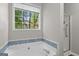 Relaxing soaking tub with blue tile accents, window views, and separate shower at 205 N Strathmore Dr, Sharpsburg, GA 30277