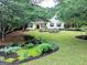 Charming home featuring a well-manicured front yard with garden beds and lush greenery at 205 N Strathmore Dr, Sharpsburg, GA 30277