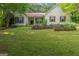 Inviting single-story home with a well-manicured lawn and charming exterior details, including shutters and a garden at 205 N Strathmore Dr, Sharpsburg, GA 30277