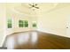 Bedroom featuring a tray ceiling, three windows overlooking a yard, and dark hardwood floors at 2589 Lake Erma Dr, Hampton, GA 30228