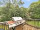 Outdoor wooden deck featuring a stainless steel grill with a serene backdrop of lush green trees at 140 Joshua St, Palmetto, GA 30268