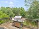 Outdoor wooden deck featuring a stainless steel grill with a serene backdrop of lush green trees at 140 Joshua St, Palmetto, GA 30268