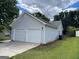 Two-car garage with an adjacent lawn and mature trees at 3081 Regal Dr, Mcdonough, GA 30253