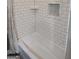 Bright white tiled bathtub and shower combination with built-in soap niche at 57 Deer Creek Run, Moreland, GA 30259