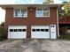 Red brick home featuring a two-car garage with white doors and white framed windows above at 363 Seminole Drs, Marietta, GA 30060