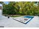 An inviting pool with a unique sunken lounge area and stepping stones surrounded by a beautiful green landscape at 490 Mount Paran Rd, Atlanta, GA 30327