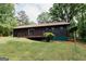 A charming single story home with an outdoor deck and lush green lawn surrounded by lush trees at 134 Ashwood Dr, Waco, GA 30182