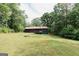 A charming single story home with a lush green lawn and rockscaping surrounded by lush trees at 134 Ashwood Dr, Waco, GA 30182
