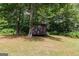 Wooden storage shed nestled among trees in a spacious, grassy backyard at 134 Ashwood Dr, Waco, GA 30182