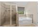Bathroom featuring a glass shower, a corner bathtub, and neutral tiling throughout at 5768 Grande River Rd, Atlanta, GA 30349