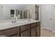 Bathroom with dual sinks, a dark wood vanity, and a door leading to a walk-in closet at 5768 Grande River Rd, Atlanta, GA 30349