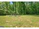 Backyard featuring garden plots, treeline, and large grassy area at 180 E Ranchette Rd, Temple, GA 30179