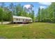 Large, grassy backyard with a wooden deck and surrounding trees at 180 E Ranchette Rd, Temple, GA 30179