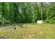Spacious backyard featuring lush greenery, raised garden beds, and a storage shed at 180 E Ranchette Rd, Temple, GA 30179
