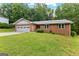 A charming brick home featuring an attached garage and a lush, green front lawn at 295 Merrydale Dr, Fayetteville, GA 30215