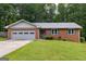 Charming brick home with a well-manicured lawn, attached garage, and lush green trees in the background at 295 Merrydale Dr, Fayetteville, GA 30215