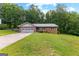 Brick house with a well maintained lawn, attached garage, and tall trees in the background at 295 Merrydale Dr, Fayetteville, GA 30215