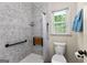 Bright, tiled shower stall with safety bars, a folding wooden bench, and a sunny window at 295 Merrydale Dr, Fayetteville, GA 30215