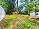 Spacious backyard with green grass and mature trees, partially enclosed by a white fence at 2502 Barge Sw Rd, Atlanta, GA 30331