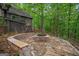 Inviting stone fire pit and seating area near home surrounded by lush greenery and trees at 9511 High Point Rd, Villa Rica, GA 30180