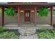 Inviting covered front porch with hanging ferns, decorative lighting, and stone accents at 9511 High Point Rd, Villa Rica, GA 30180