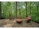 Comfortable seating area with chairs and an ottoman on a stone patio in a lush, wooded setting at 9511 High Point Rd, Villa Rica, GA 30180