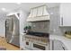 Updated kitchen featuring stainless steel appliances, white cabinets, gold accents, and a decorative white range hood at 1153 Dawn View Nw Ln, Atlanta, GA 30327