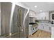 Well-lit kitchen featuring stainless steel appliances with gold handles and white cabinets, and light wood flooring at 1153 Dawn View Nw Ln, Atlanta, GA 30327