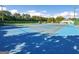 View of the blue and gray hardcourt tennis courts featuring perimeter fencing and lush surrounding trees at 440 Homeplace Dr, Stockbridge, GA 30281