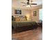 This is a cozy bedroom with a king-sized bed, wood flooring, and a ceiling fan at 60 Carriage Gate Dr, Sharpsburg, GA 30277